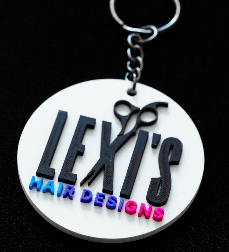 A round keychain with a hair salon logo in relief